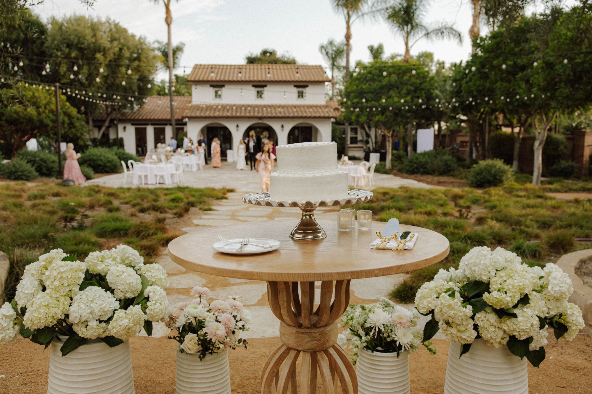 Wedding cake table surrounded by white hydrangeas