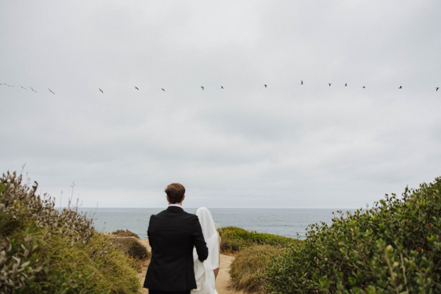 Couple walking toward the ocean on a coastal path